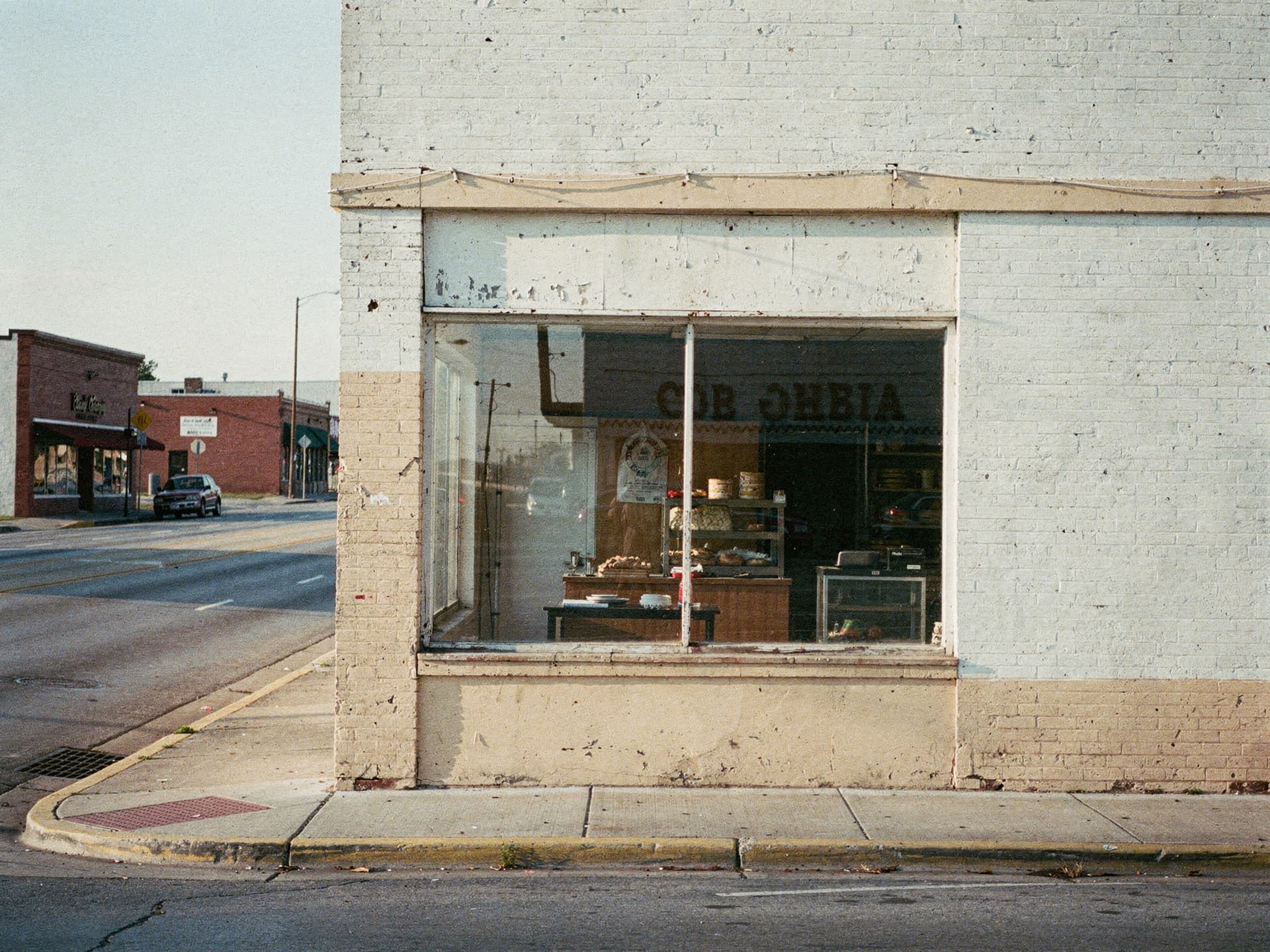 A quiet corner bakery shopfront in early morning light