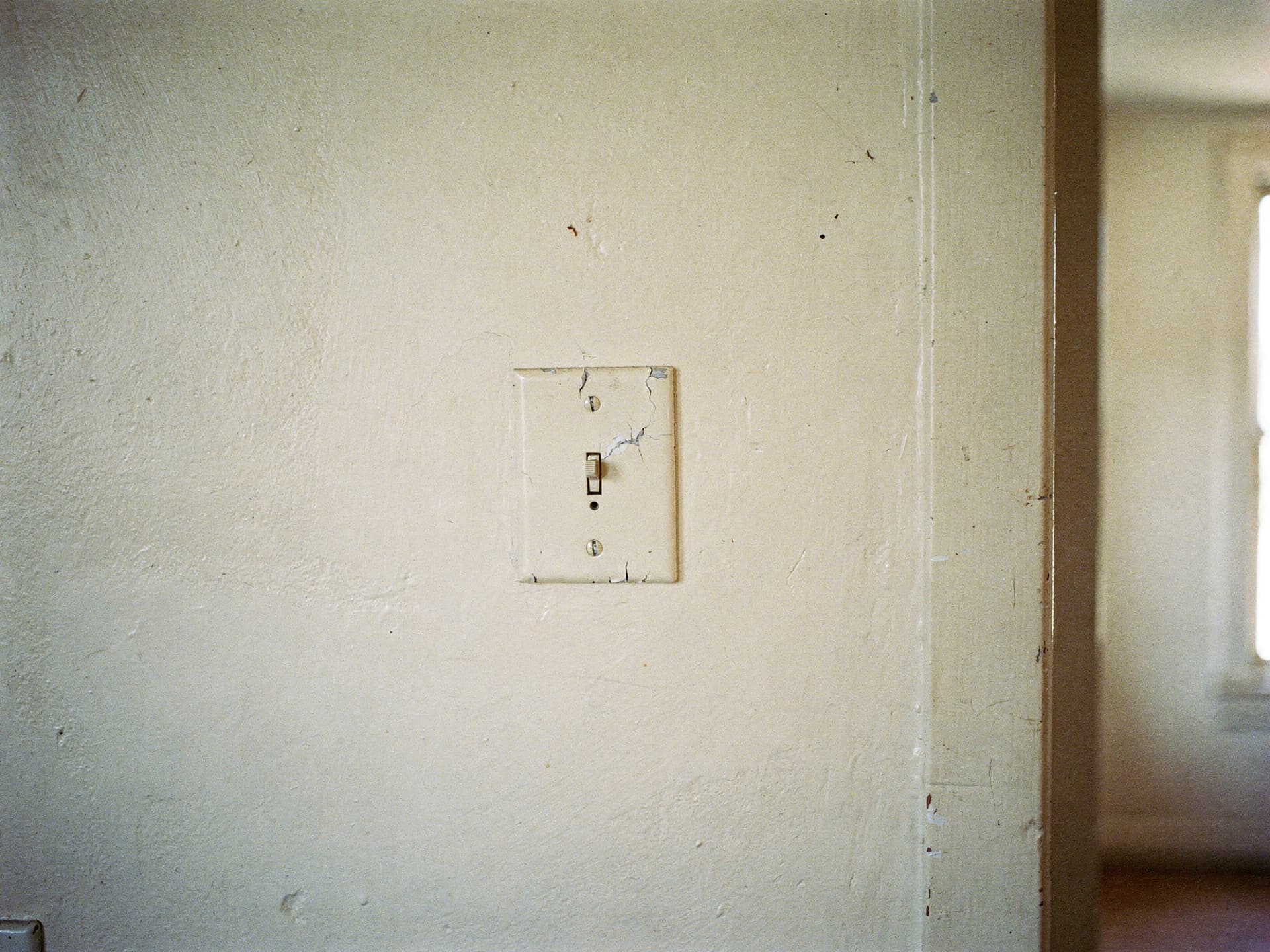 A simple mechanical light switch on a painted plaster wall in natural daylight